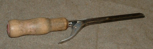 An early hair curling iron. This one has a wooden handle for safety, most had iron handles and needed to be held with fabric.